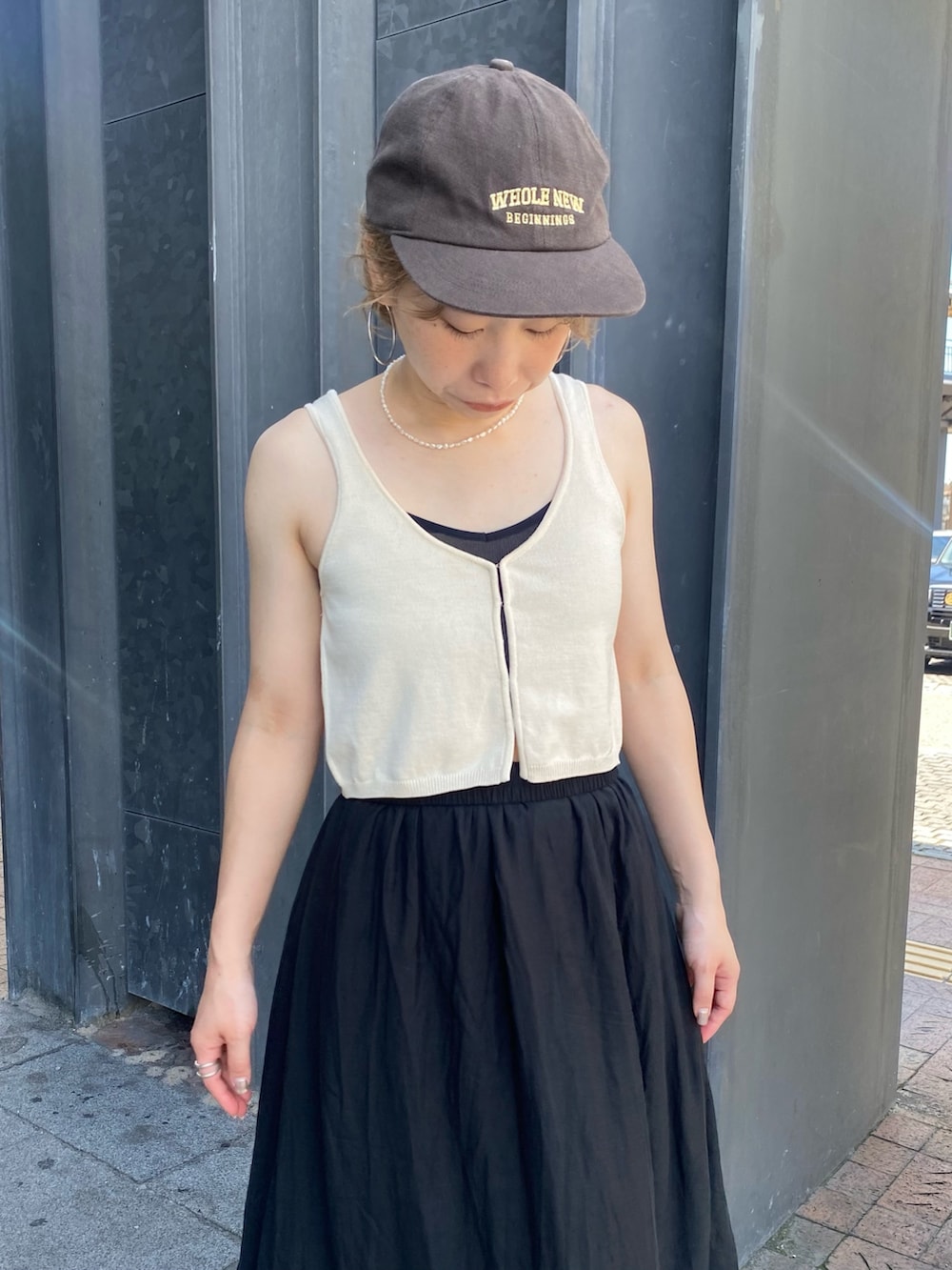 ホワイト系のベスト、ブラック系のスカートを着用したレディースの夏コーディネートの4枚目の写真