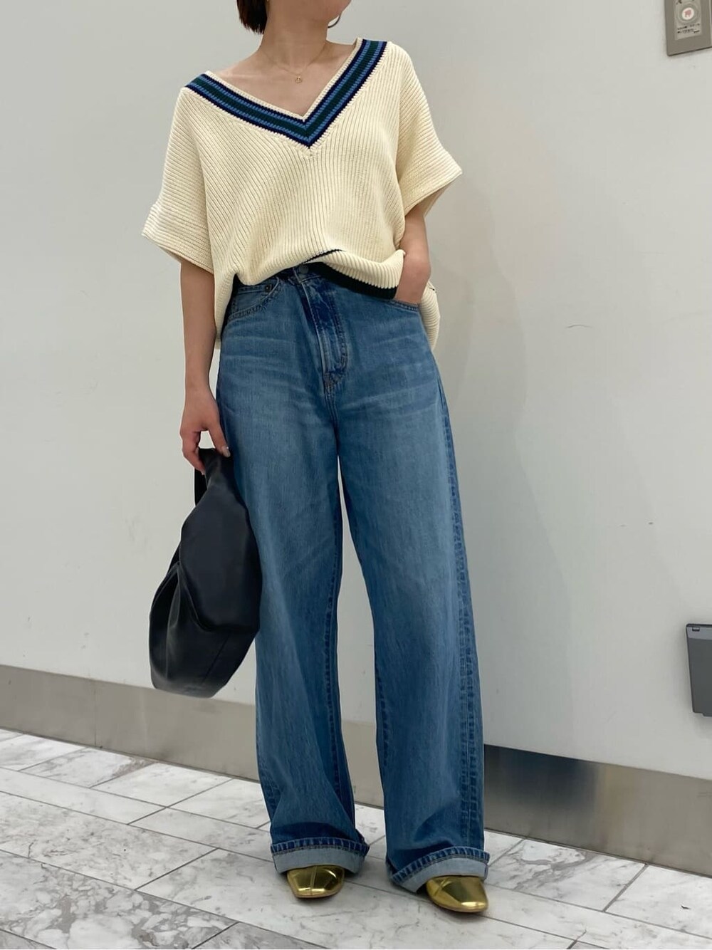 ベージュ系のトレンチコート、ゴールド系のパンプス、ブルー系のデニムパンツを着用したレディースの秋コーディネートの6枚目の写真