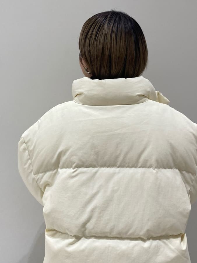 グレー系のスカート、ホワイト系のダウンジャケット/コート、ブラック系のニット/セーターを着用したレディースの秋コーディネートの3枚目の写真