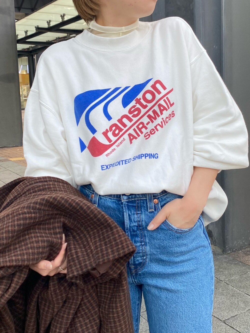 ホワイト系のスウェット、ブラウン系のその他アウター、ブルー系のデニムパンツを着用したレディースの冬コーディネートの2枚目の写真