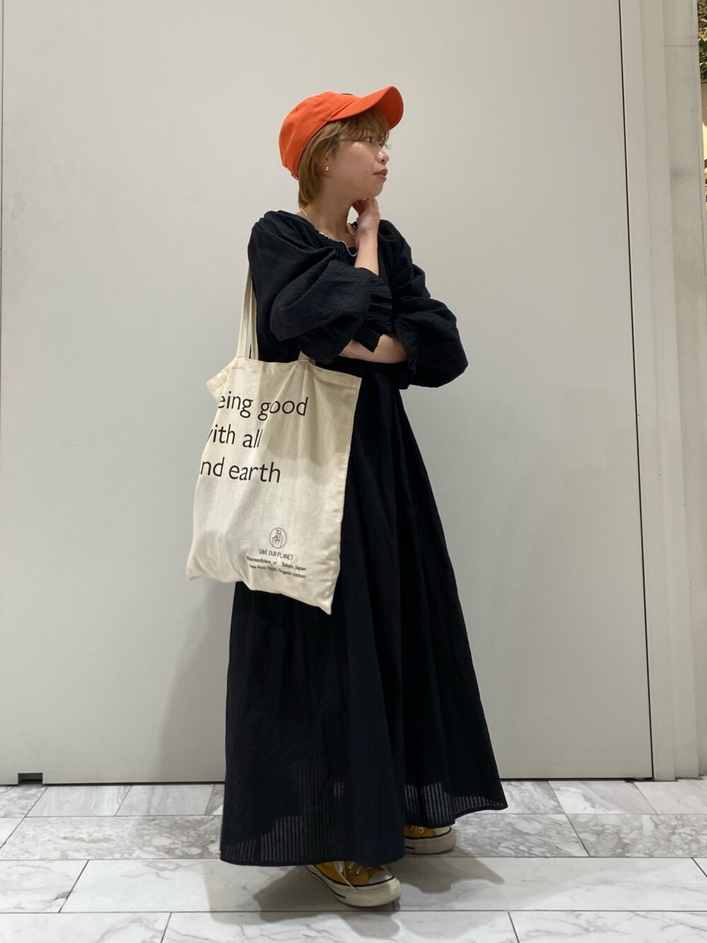 ブラック系のワンピース、オレンジ系のキャップを着用したレディースの春コーディネートの2枚目の写真