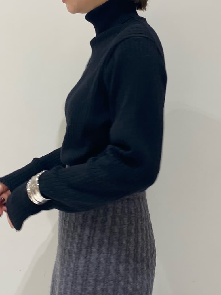 グレー系のスカート、ホワイト系のダウンジャケット/コート、ブラック系のニット/セーターを着用したレディースの秋コーディネートの5枚目の写真