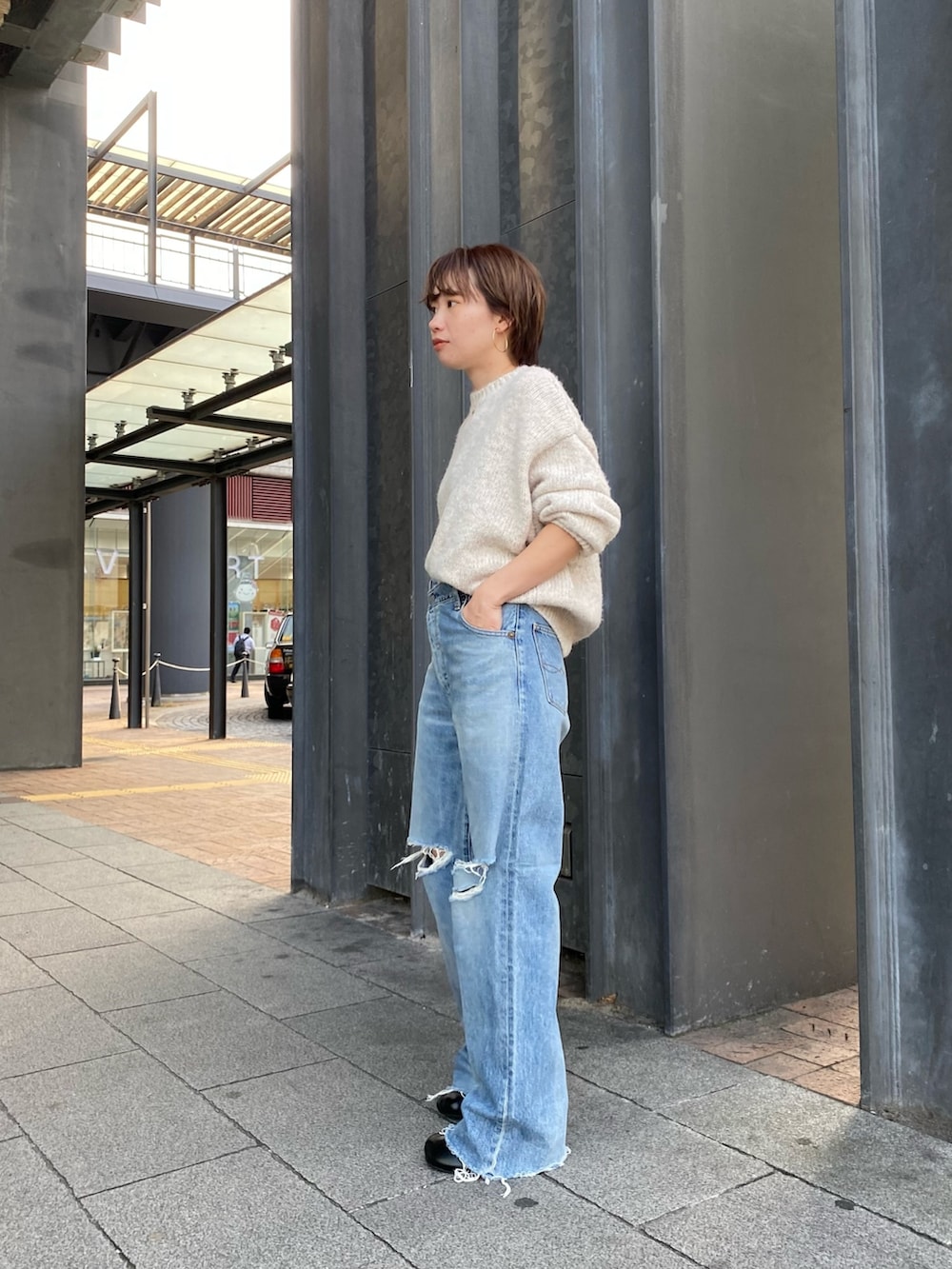 ブラック系のブーツ、ブルー系のデニムパンツ、ブラック系のハンドバッグを着用したレディースの秋コーディネートの2枚目の写真