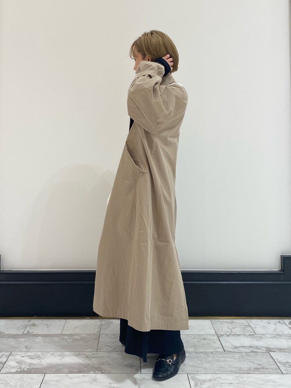 ベージュ系のステンカラーコートを着用したレディースの春コーディネートの3枚目の写真