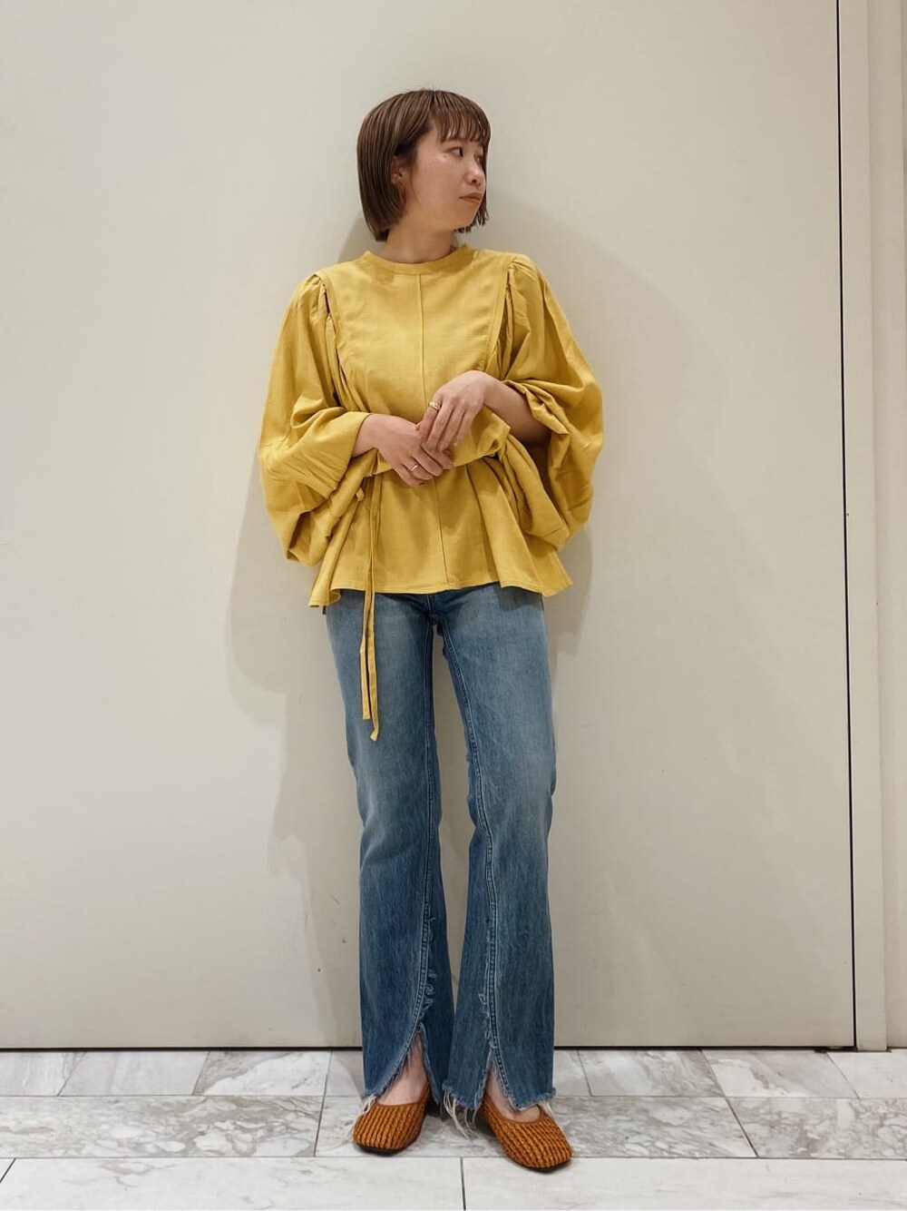 ブラウン系のパンプス、イエロー系のシャツ/ブラウス、ブルー系のデニムパンツを着用したレディースの春コーディネートの4枚目の写真