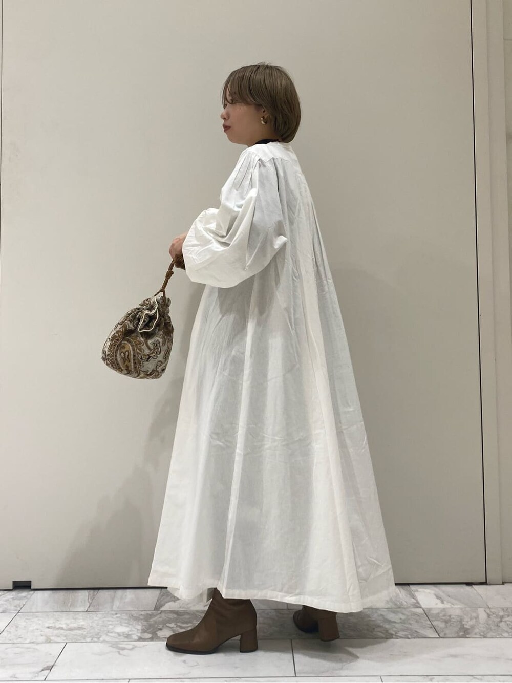 ホワイト系のハンドバッグ、ホワイト系のワンピースを着用したレディースの秋コーディネートの3枚目の写真