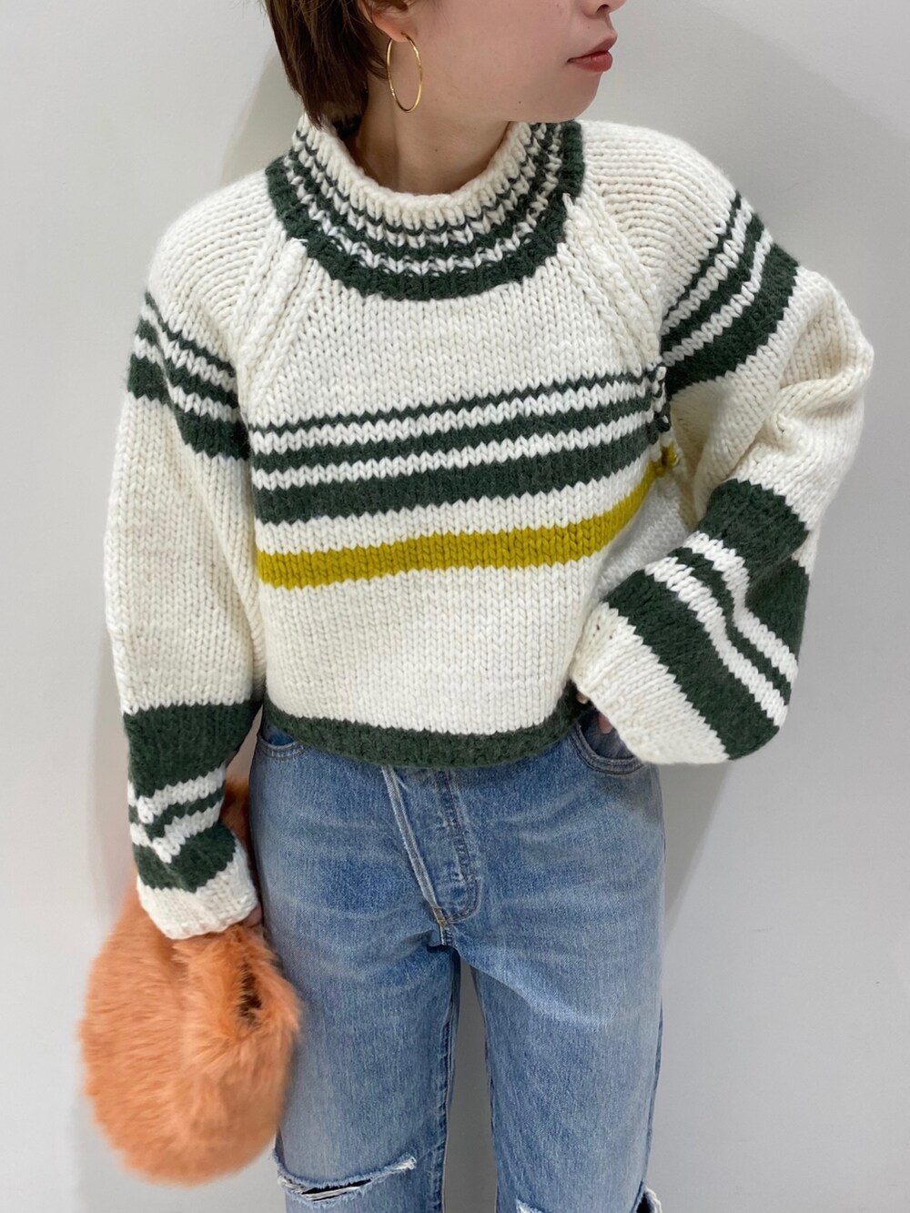 ブラック系のブーツ、オレンジ系のハンドバッグ、ブルー系のデニムパンツを着用したレディースの秋コーディネートの4枚目の写真