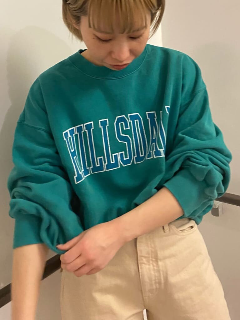 ベージュ系のステンカラーコート、グリーン系のスウェット、ホワイト系のデニムパンツを着用したレディースの冬コーディネートの2枚目の写真