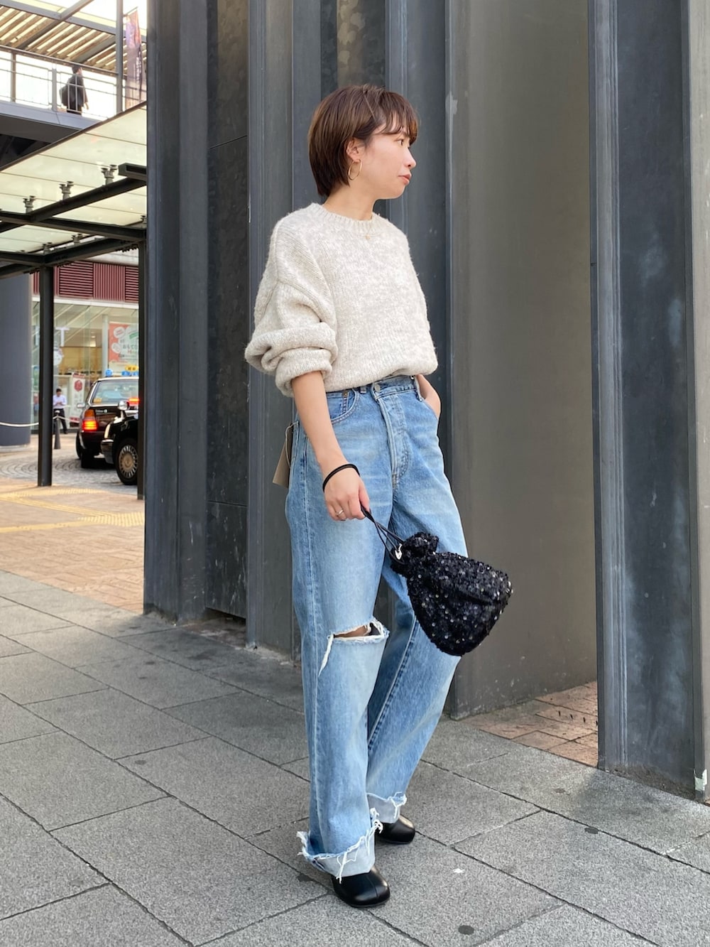 ブラック系のブーツ、ブルー系のデニムパンツ、ブラック系のハンドバッグを着用したレディースの秋コーディネートの3枚目の写真