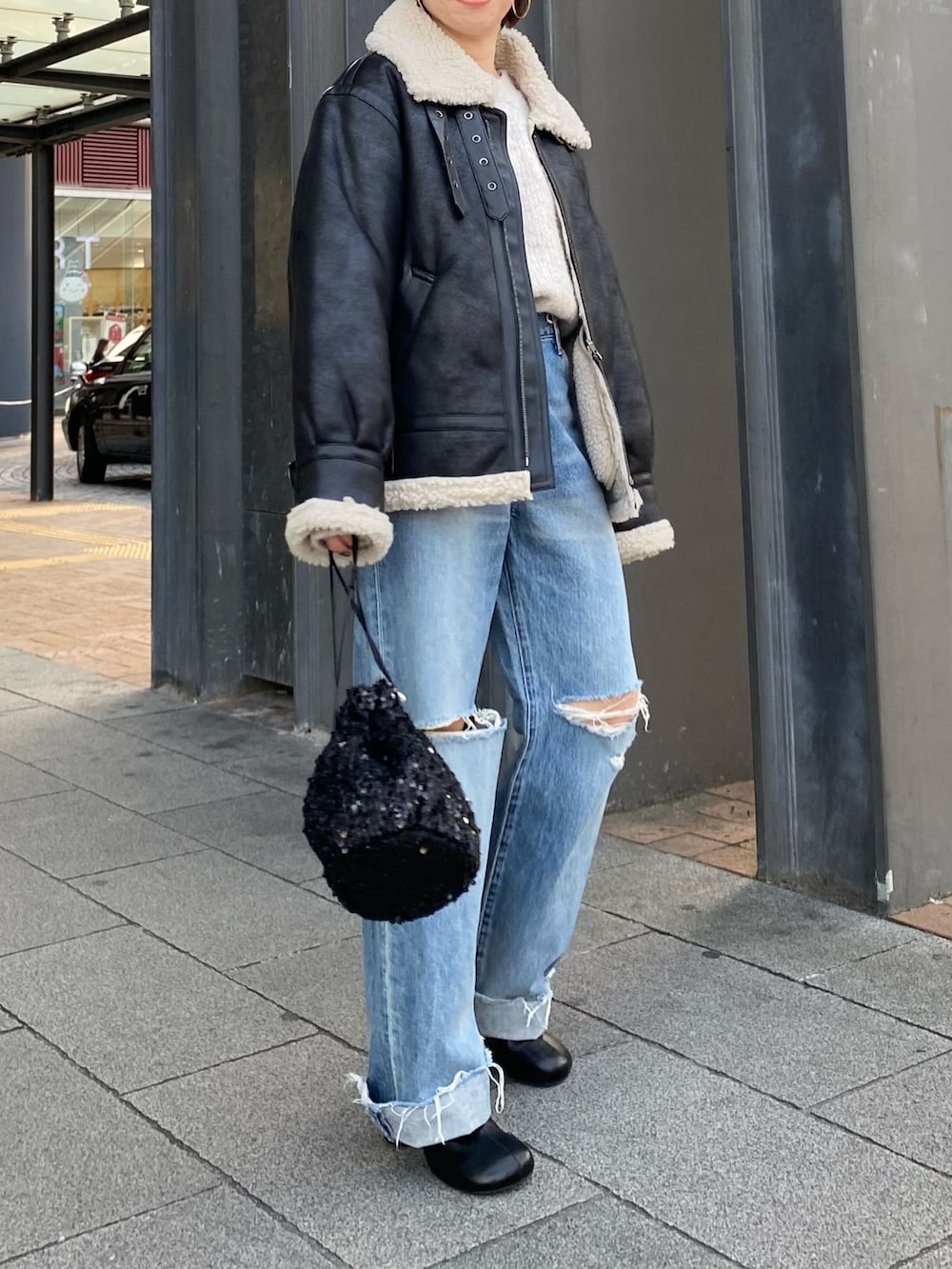 ブラック系のブーツ、ブルー系のデニムパンツ、ブラック系のハンドバッグを着用したレディースの秋コーディネートの4枚目の写真