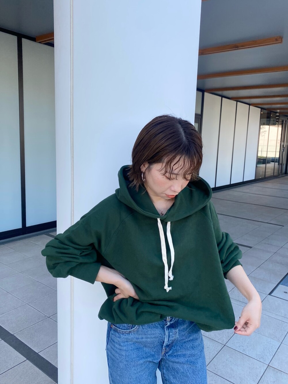 グリーン系のパーカー、ブルー系のデニムパンツを着用したレディースの秋コーディネートの2枚目の写真