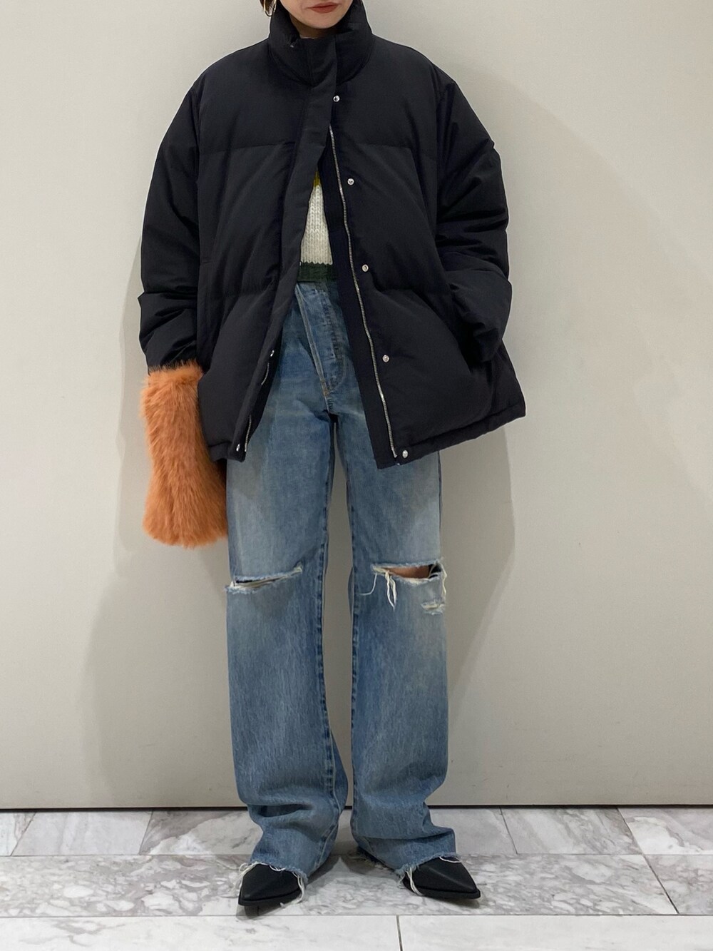 ブラック系のブーツ、オレンジ系のハンドバッグ、ブルー系のデニムパンツを着用したレディースの秋コーディネートの5枚目の写真