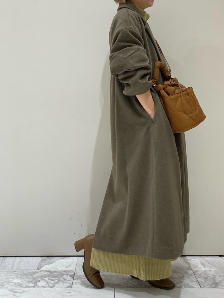 ブラック系のTシャツ/カットソー、ブラウン系のチェスターコート、グリーン系のワンピースを着用したレディースの冬コーディネートの6枚目の写真