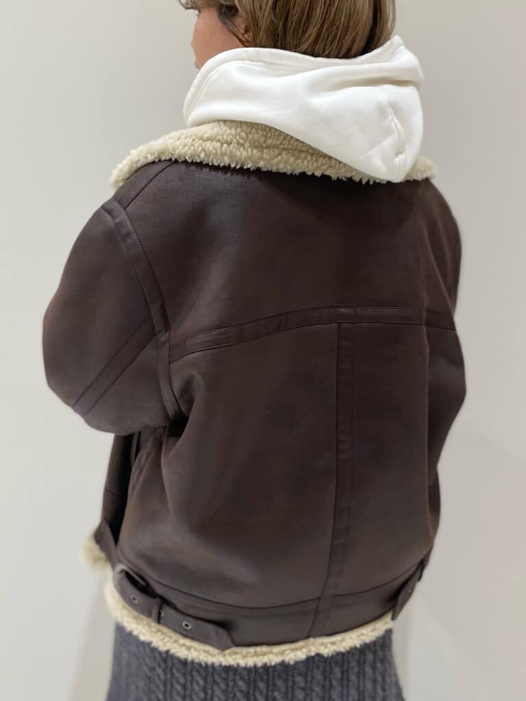 ブラウン系のブルゾン、ホワイト系のパーカー、グレー系のスカートを着用したレディースの秋コーディネートの5枚目の写真