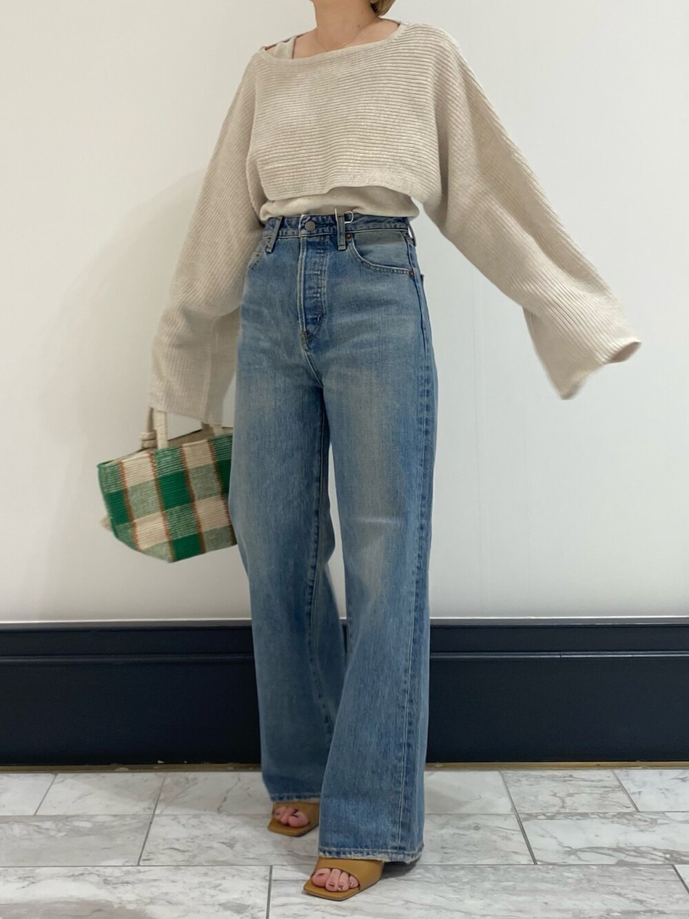 ブルー系のデニムパンツ、ホワイト系のニット/セーターを着用したレディースの春コーディネートの3枚目の写真