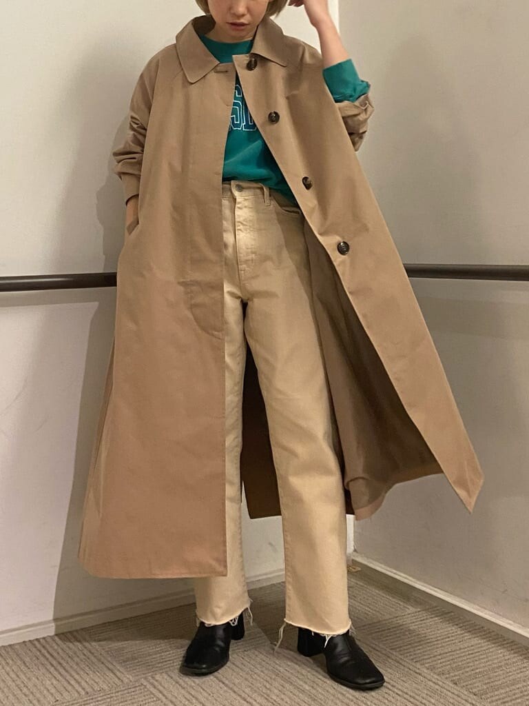 ベージュ系のステンカラーコート、グリーン系のスウェット、ホワイト系のデニムパンツを着用したレディースの冬コーディネートの4枚目の写真