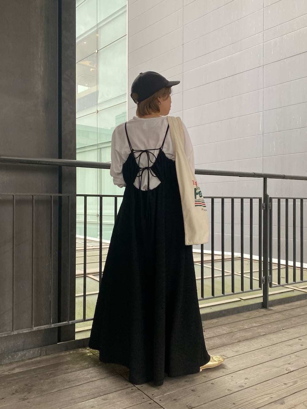 ブラック系のワンピース、イエロー系のパンプス、グリーン系のトートバッグを着用したレディースの春コーディネートの4枚目の写真