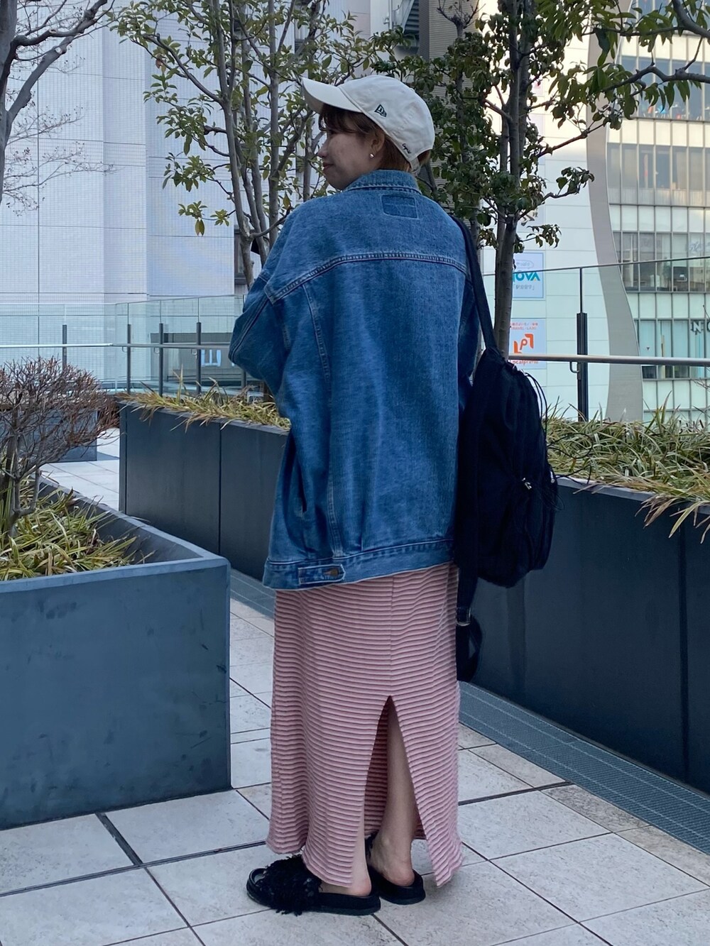 ピンク系のワンピース、ブルー系のデニムジャケット、ブラック系のバックパック/リュックを着用したレディースの冬コーディネートの2枚目の写真