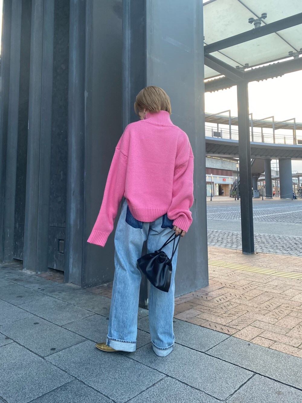 ピンク系のニット/セーター、ブルー系のデニムパンツ、ブラック系のクラッチバッグを着用したレディースの秋コーディネートの3枚目の写真