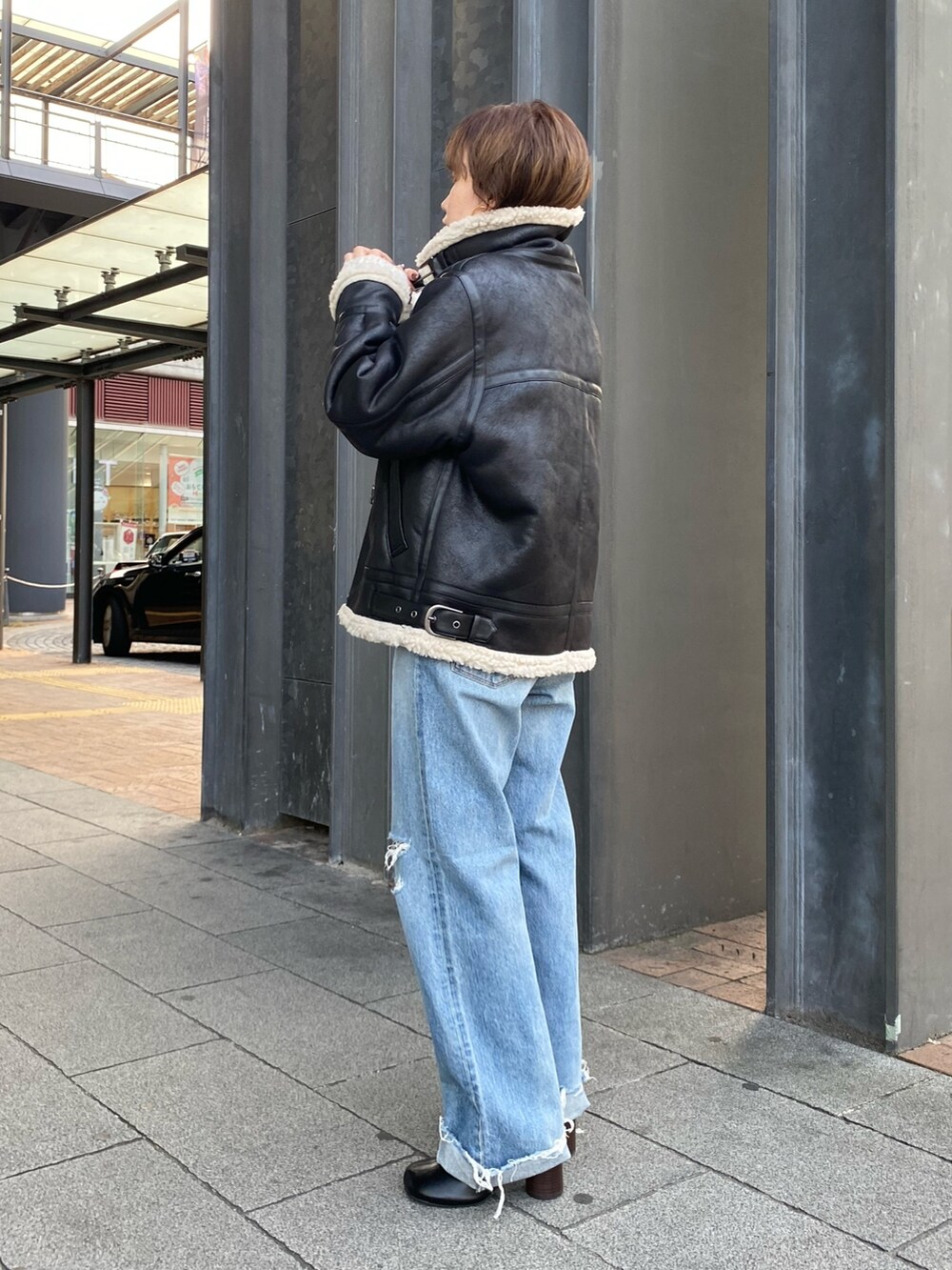 ブラック系のブーツ、ブルー系のデニムパンツ、ブラック系のハンドバッグを着用したレディースの秋コーディネートの5枚目の写真