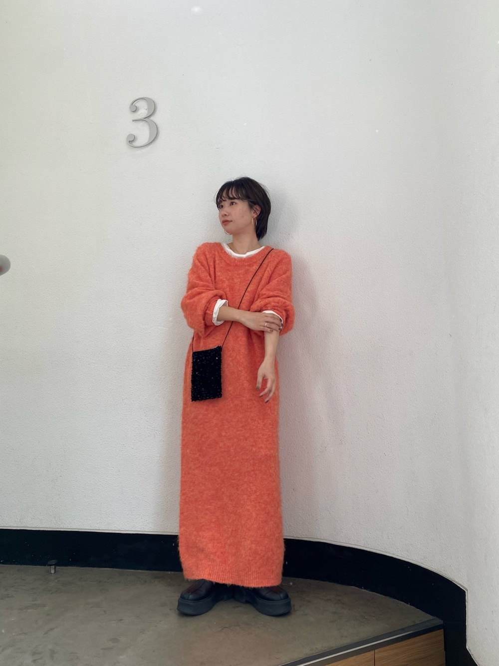 オレンジ系のワンピース、ブラック系のショルダーバッグ、ホワイト系のTシャツ/カットソーを着用したレディースの秋コーディネートの3枚目の写真