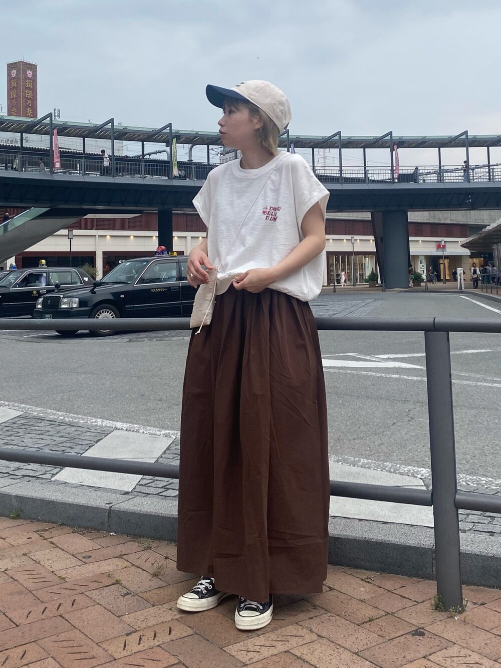 ホワイト系のTシャツ/カットソー、ブラウン系のワンピース、ホワイト系のショルダーバッグを着用したレディースの春コーディネートの2枚目の写真