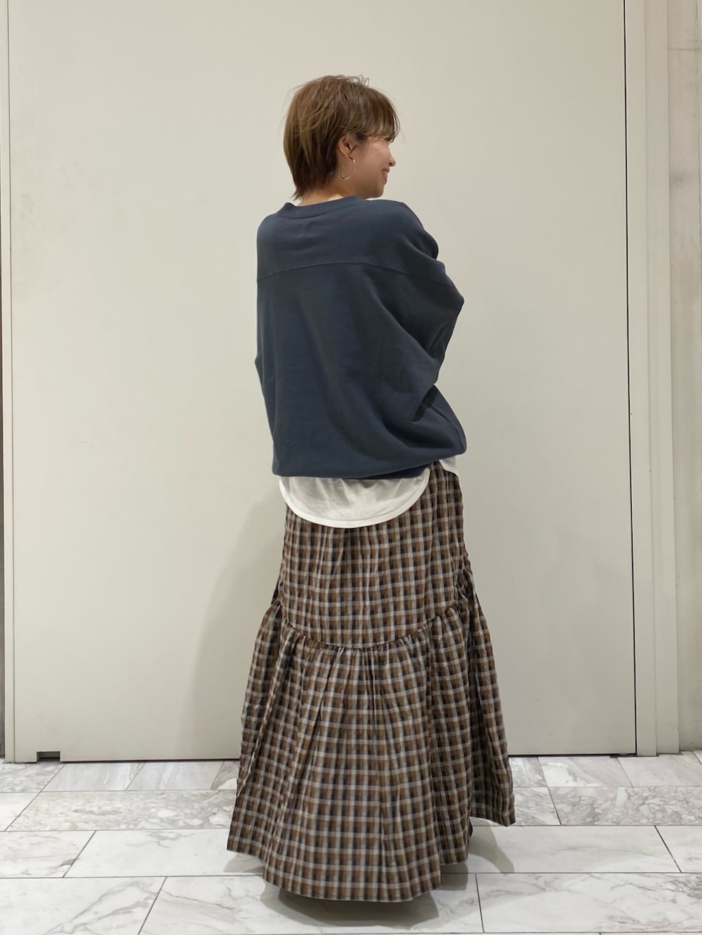 グレー系のスウェット、ブラウン系のスカート、ホワイト系のTシャツ/カットソーを着用したレディースの冬コーディネートの3枚目の写真