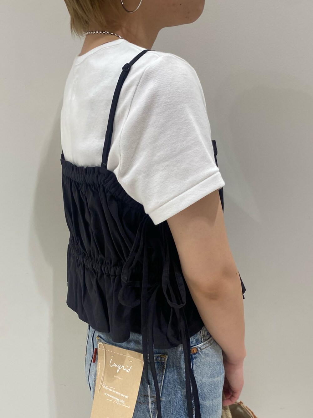 ブラック系のワンピース、ホワイト系のTシャツ/カットソー、ゴールド系のパンプスを着用したレディースの春コーディネートの5枚目の写真
