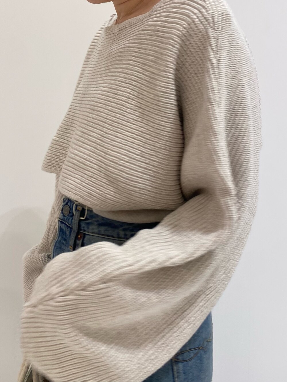 ブルー系のデニムパンツ、ホワイト系のニット/セーターを着用したレディースの春コーディネートの5枚目の写真