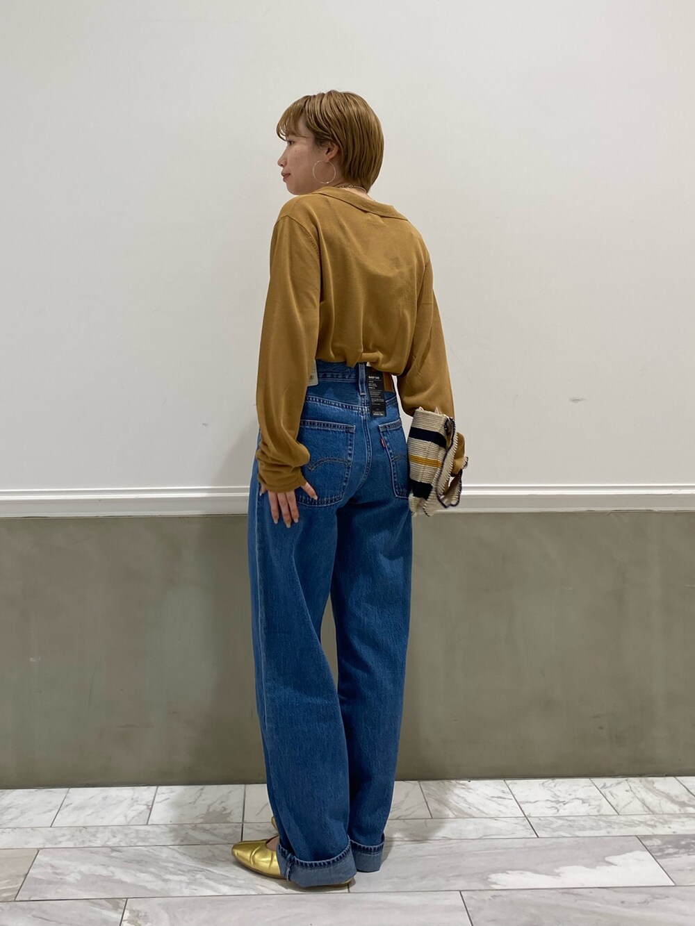 イエロー系のカーディガン/ボレロ、ホワイト系のハンドバッグを着用したレディースの春コーディネートの2枚目の写真