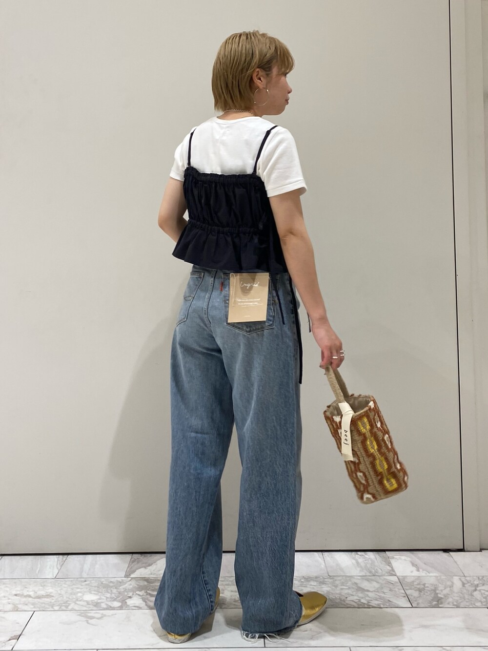 ブラック系のワンピース、ホワイト系のTシャツ/カットソー、ゴールド系のパンプスを着用したレディースの春コーディネートの3枚目の写真