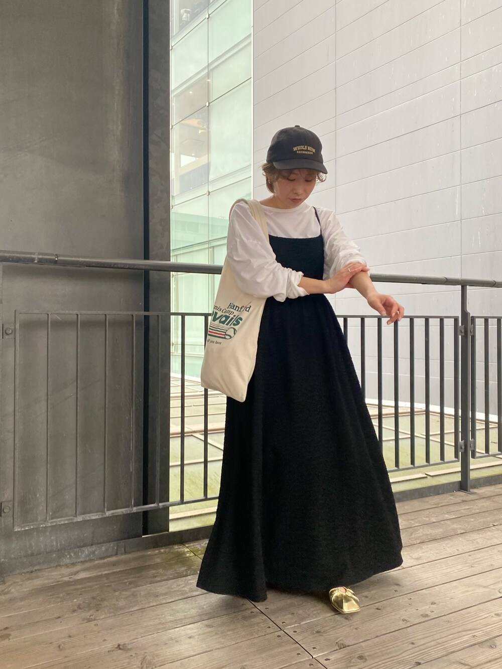 ブラック系のワンピース、イエロー系のパンプス、グリーン系のトートバッグを着用したレディースの春コーディネートの3枚目の写真