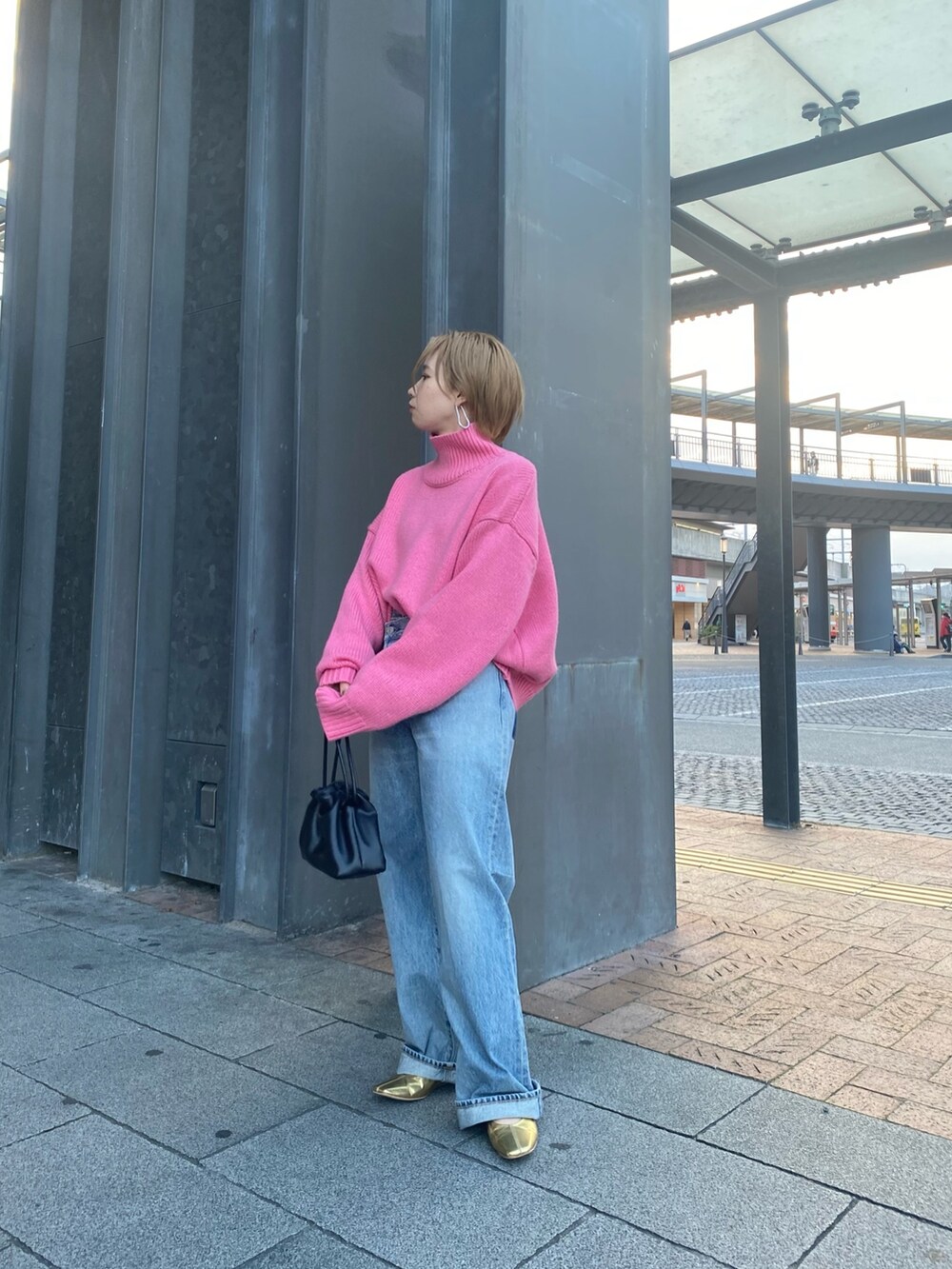 ピンク系のニット/セーター、ブルー系のデニムパンツ、ブラック系のクラッチバッグを着用したレディースの秋コーディネートの2枚目の写真