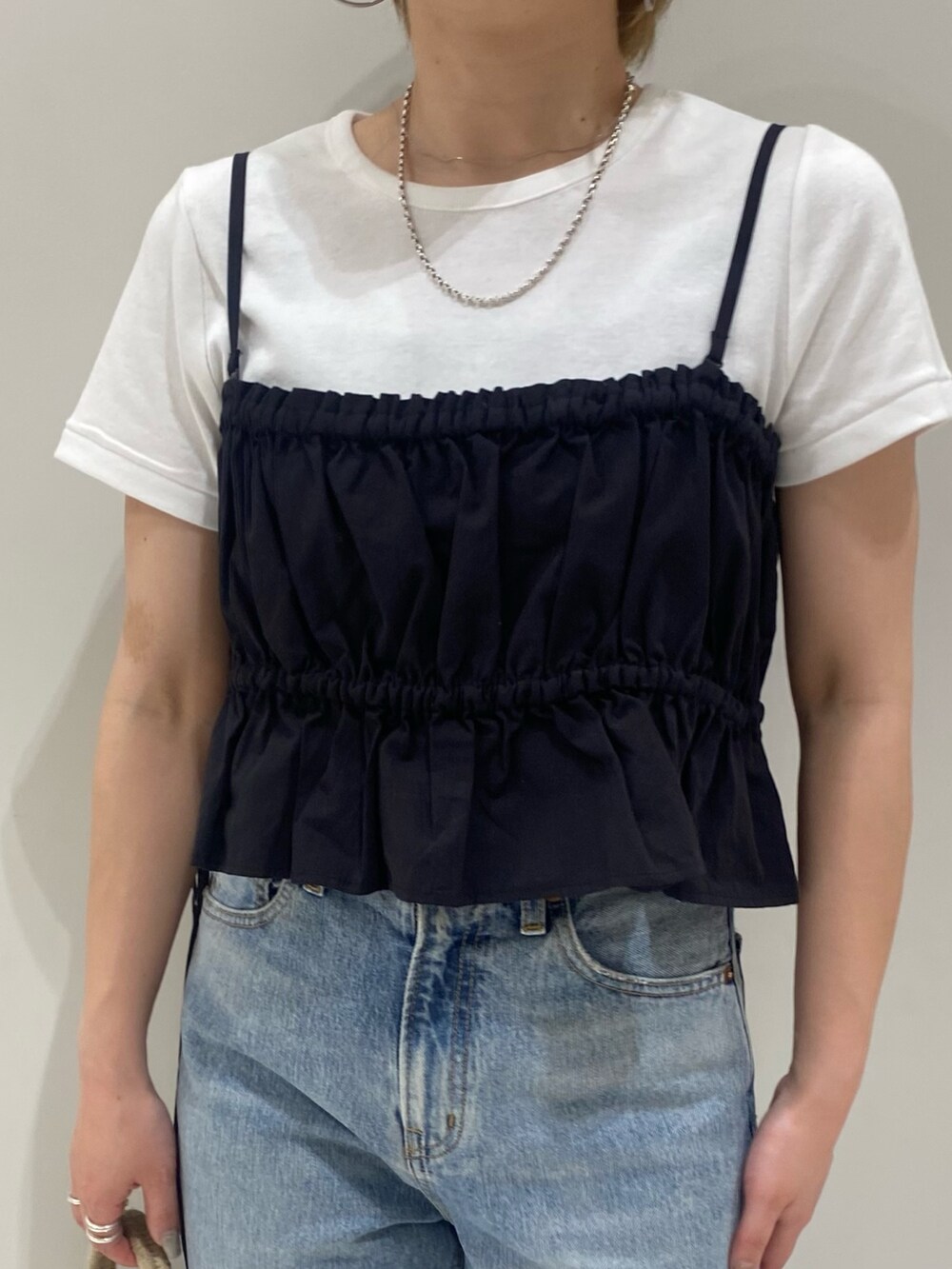 ブラック系のワンピース、ホワイト系のTシャツ/カットソー、ゴールド系のパンプスを着用したレディースの春コーディネートの4枚目の写真