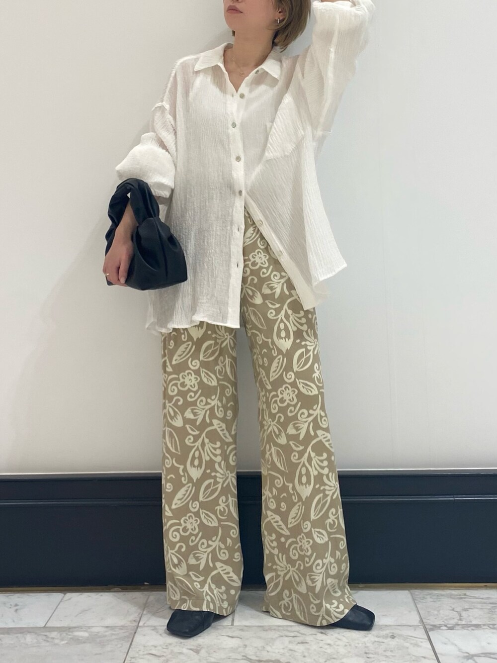 ブラック系のパンプス、ホワイト系のシャツ/ブラウス、ブラック系のハンドバッグを着用したレディースの春コーディネートの2枚目の写真