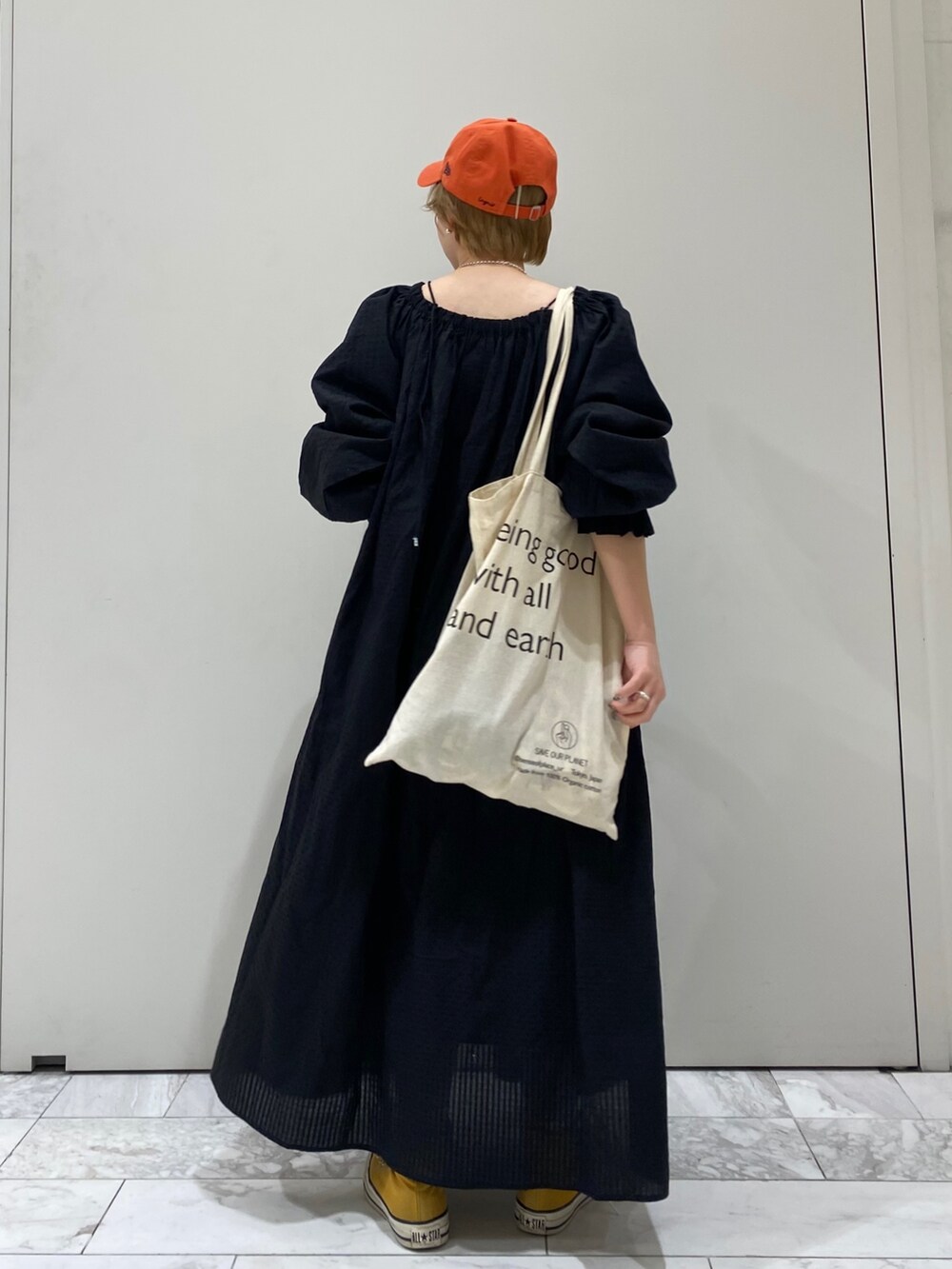 ブラック系のワンピース、オレンジ系のキャップを着用したレディースの春コーディネートの4枚目の写真