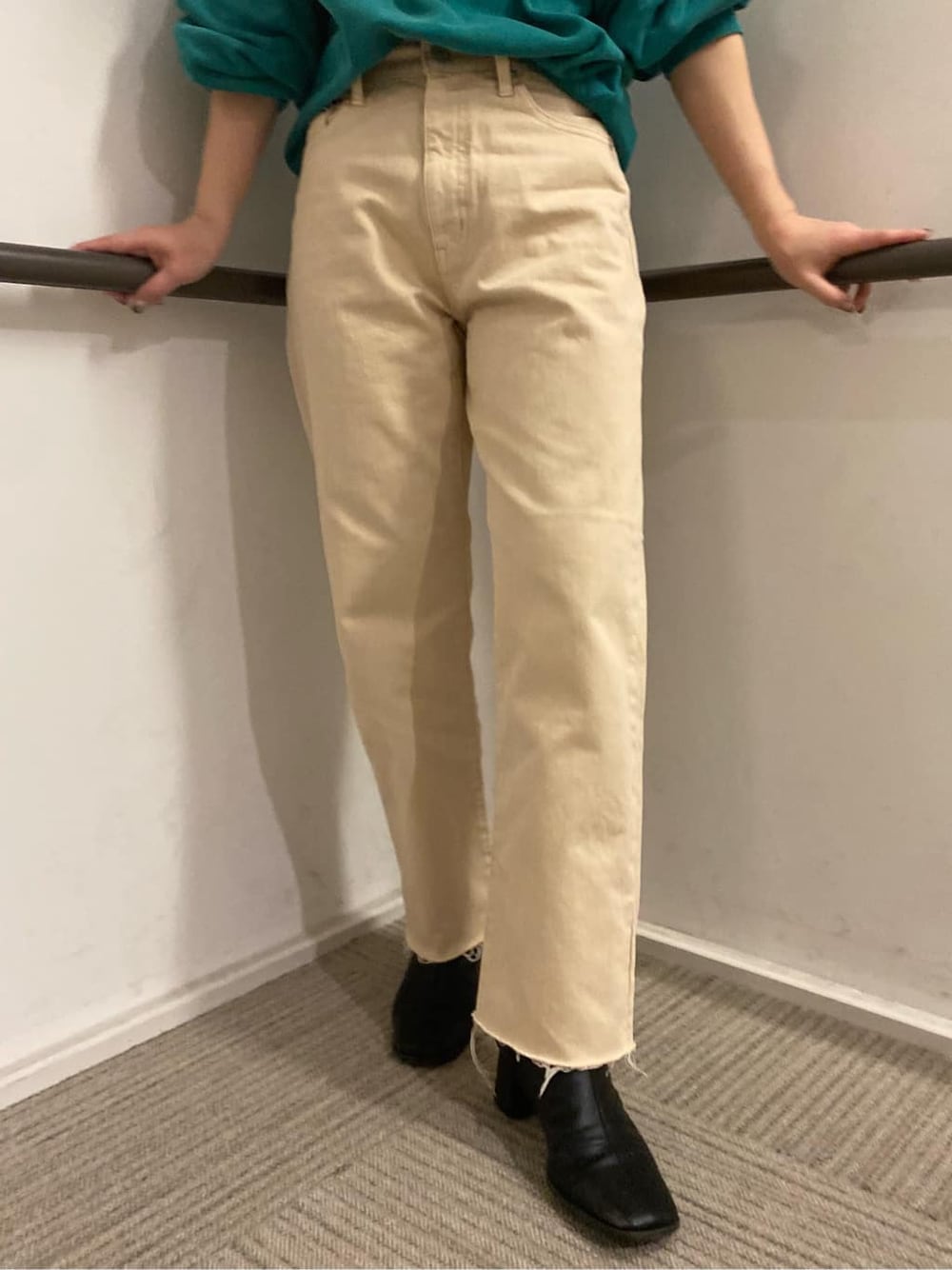 ベージュ系のステンカラーコート、グリーン系のスウェット、ホワイト系のデニムパンツを着用したレディースの冬コーディネートの3枚目の写真