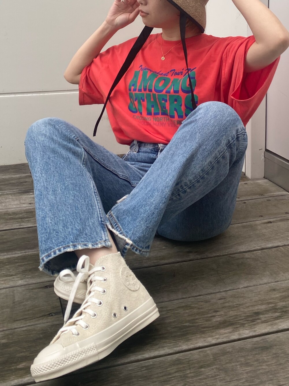 オレンジ系のTシャツ/カットソー、ホワイト系のスニーカー、ベージュ系のハットを着用したレディースの春コーディネートの3枚目の写真