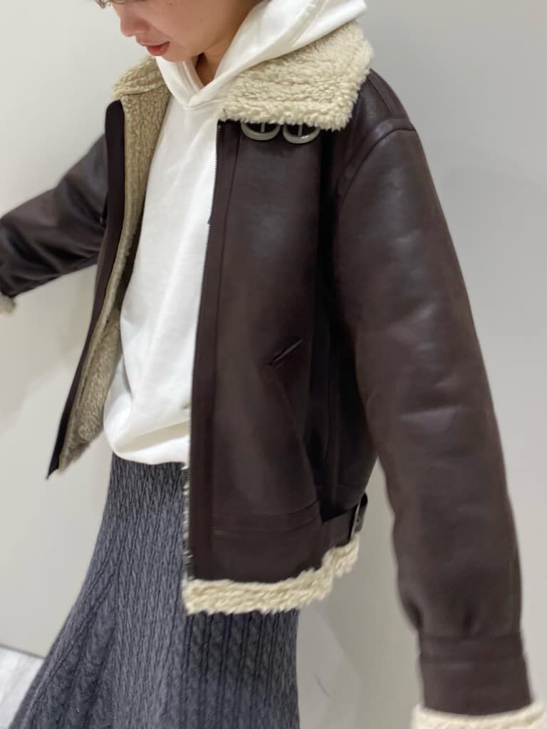 ブラウン系のブルゾン、ホワイト系のパーカー、グレー系のスカートを着用したレディースの秋コーディネートの6枚目の写真