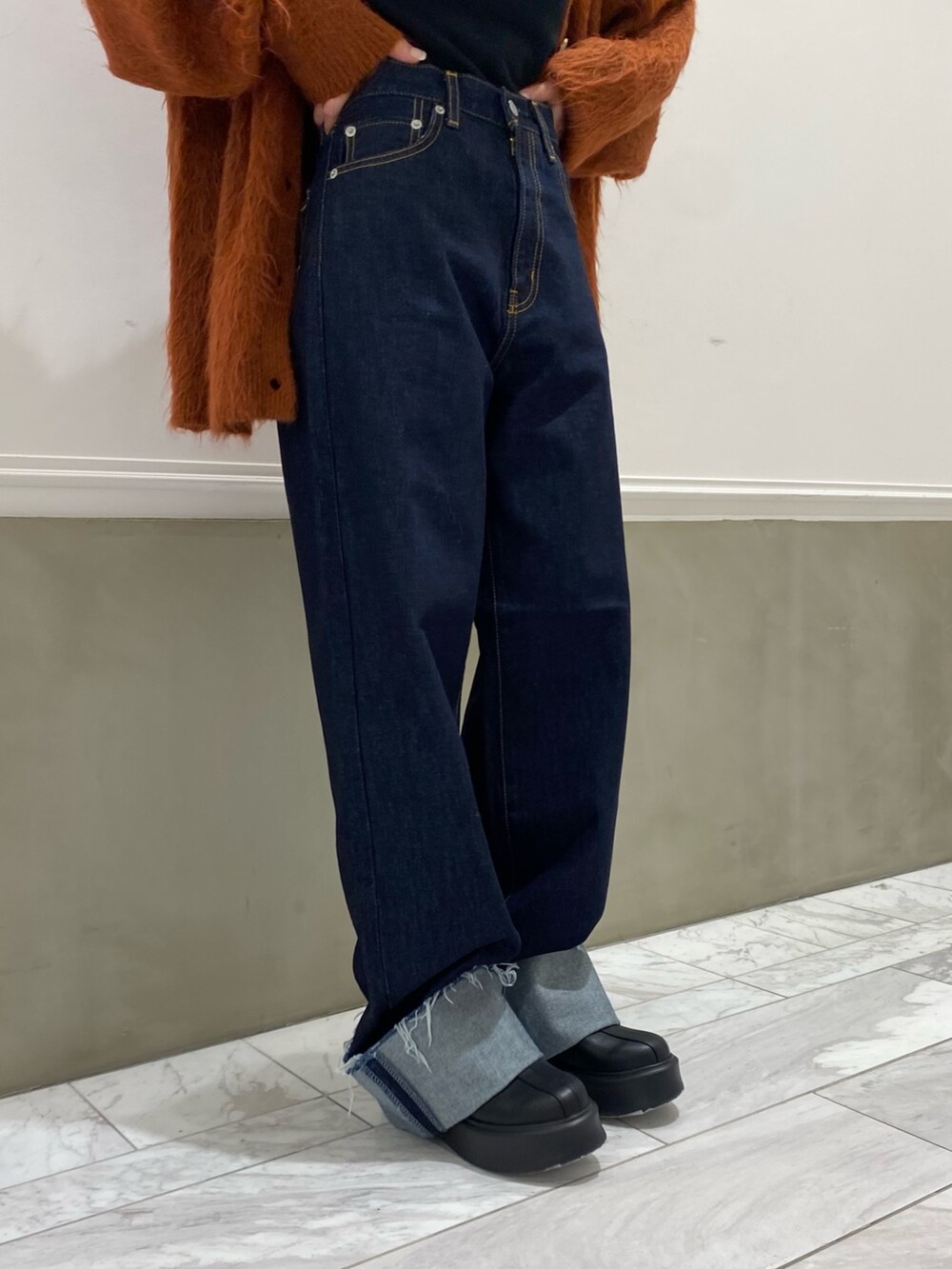 ブルー系のデニムパンツ、オレンジ系のカーディガン/ボレロ、ブラック系のハットを着用したレディースの秋コーディネートの5枚目の写真