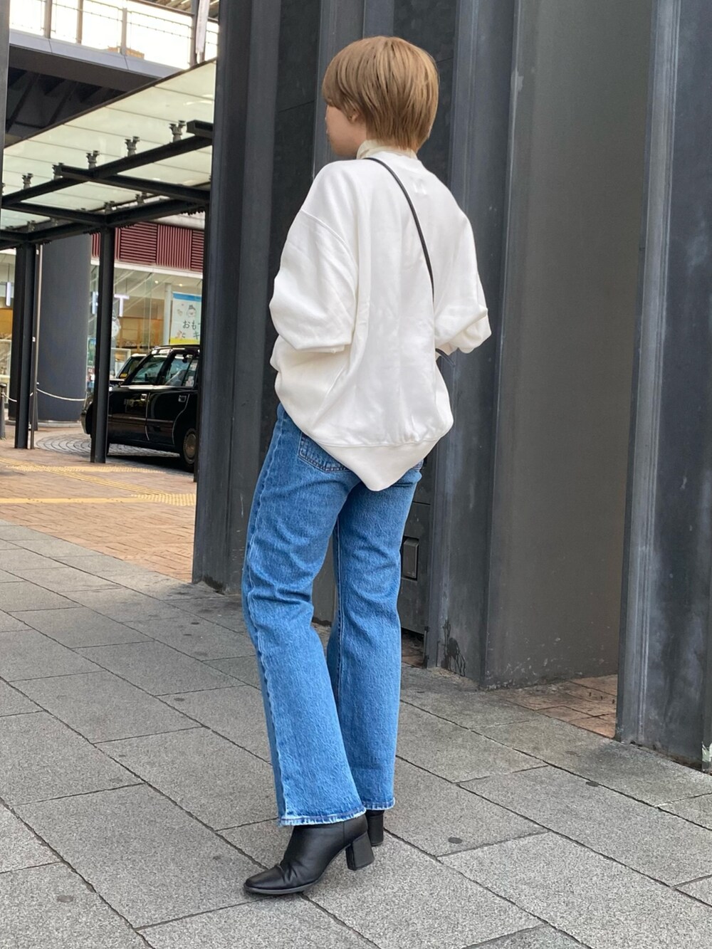 ホワイト系のスウェット、ブラウン系のその他アウター、ブルー系のデニムパンツを着用したレディースの冬コーディネートの3枚目の写真