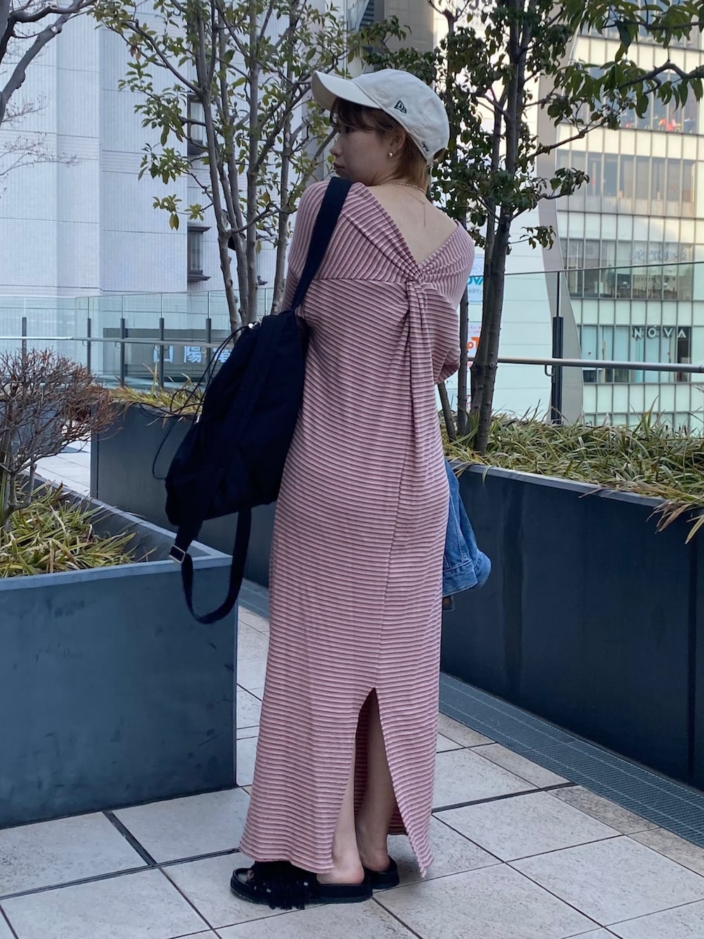 ピンク系のワンピース、ブルー系のデニムジャケット、ブラック系のバックパック/リュックを着用したレディースの冬コーディネートの4枚目の写真