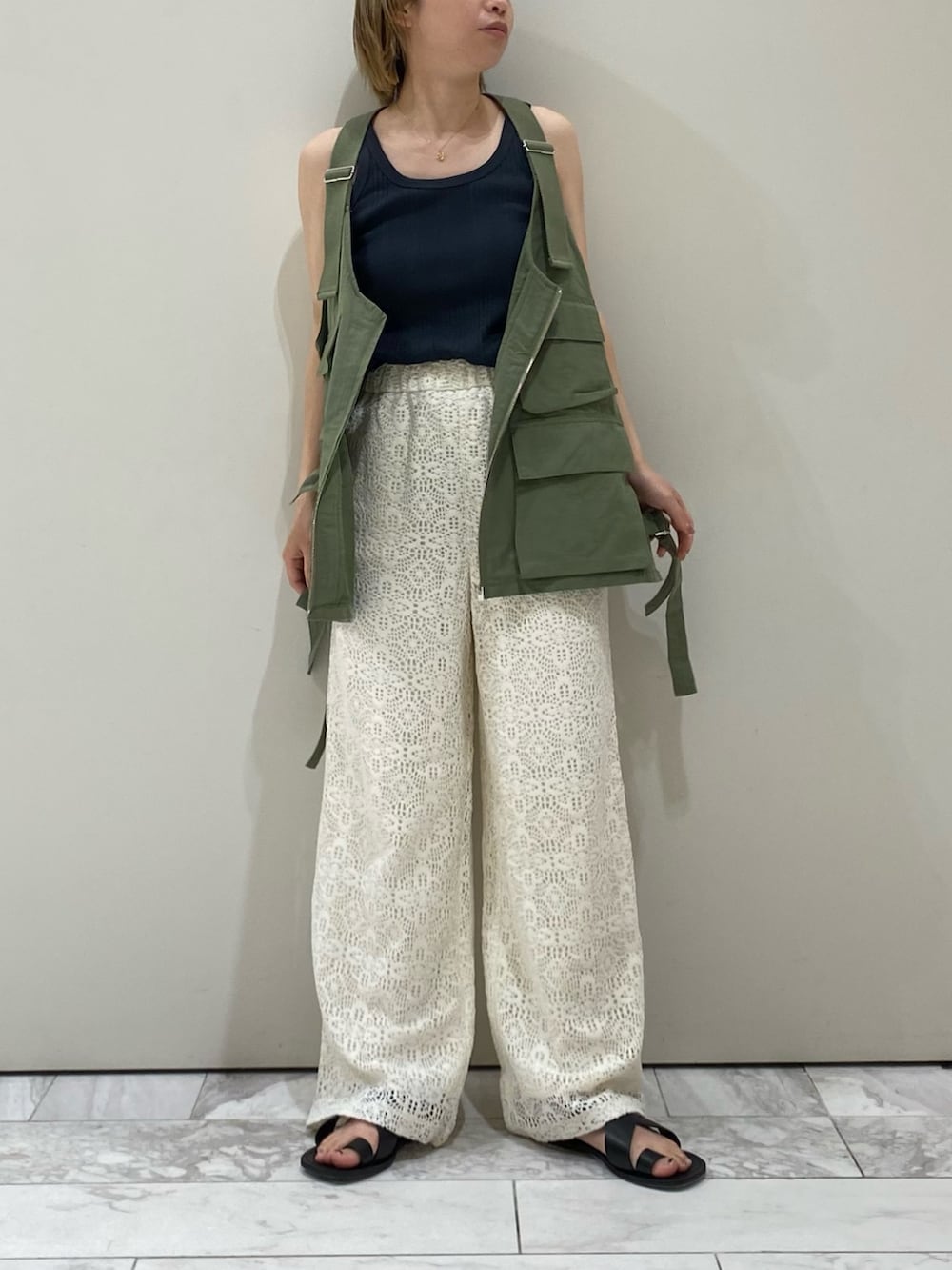 グリーン系のベスト、グレー系のタンクトップ、ホワイト系のその他パンツを着用したレディースの春コーディネートの2枚目の写真