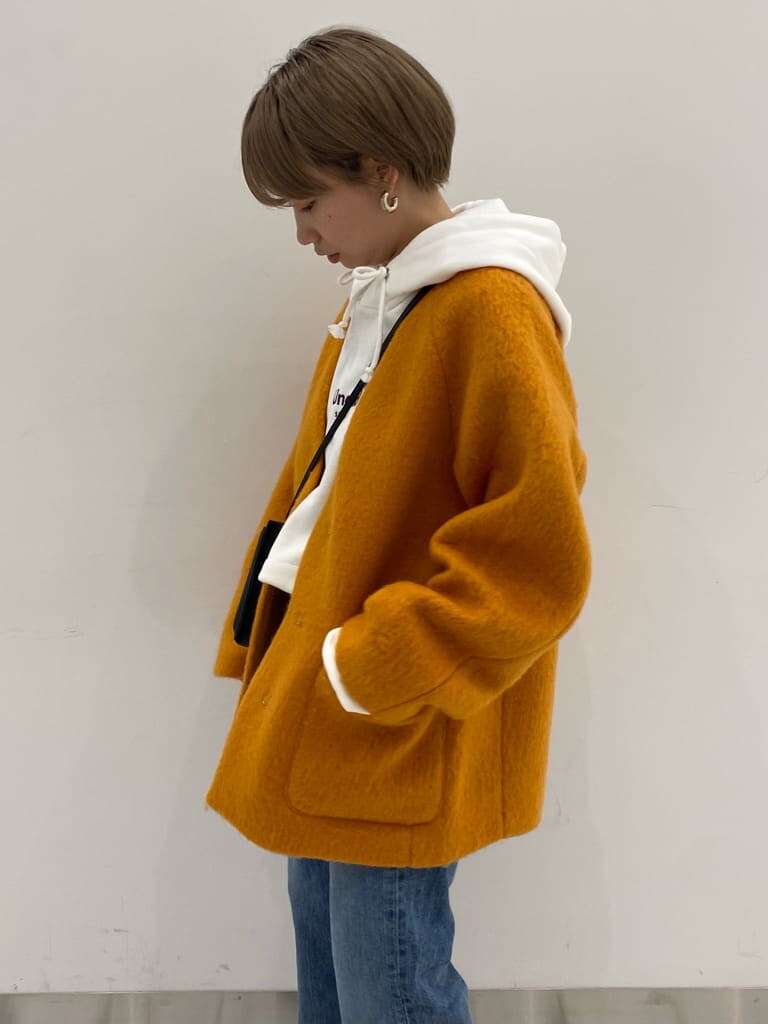 ブルー系のデニムパンツ、イエロー系のテーラードジャケット、ホワイト系のパーカーを着用したレディースの秋コーディネートの3枚目の写真