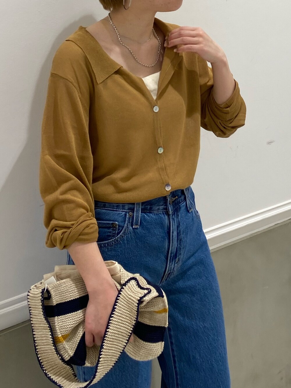 イエロー系のカーディガン/ボレロ、ホワイト系のハンドバッグを着用したレディースの春コーディネートの3枚目の写真