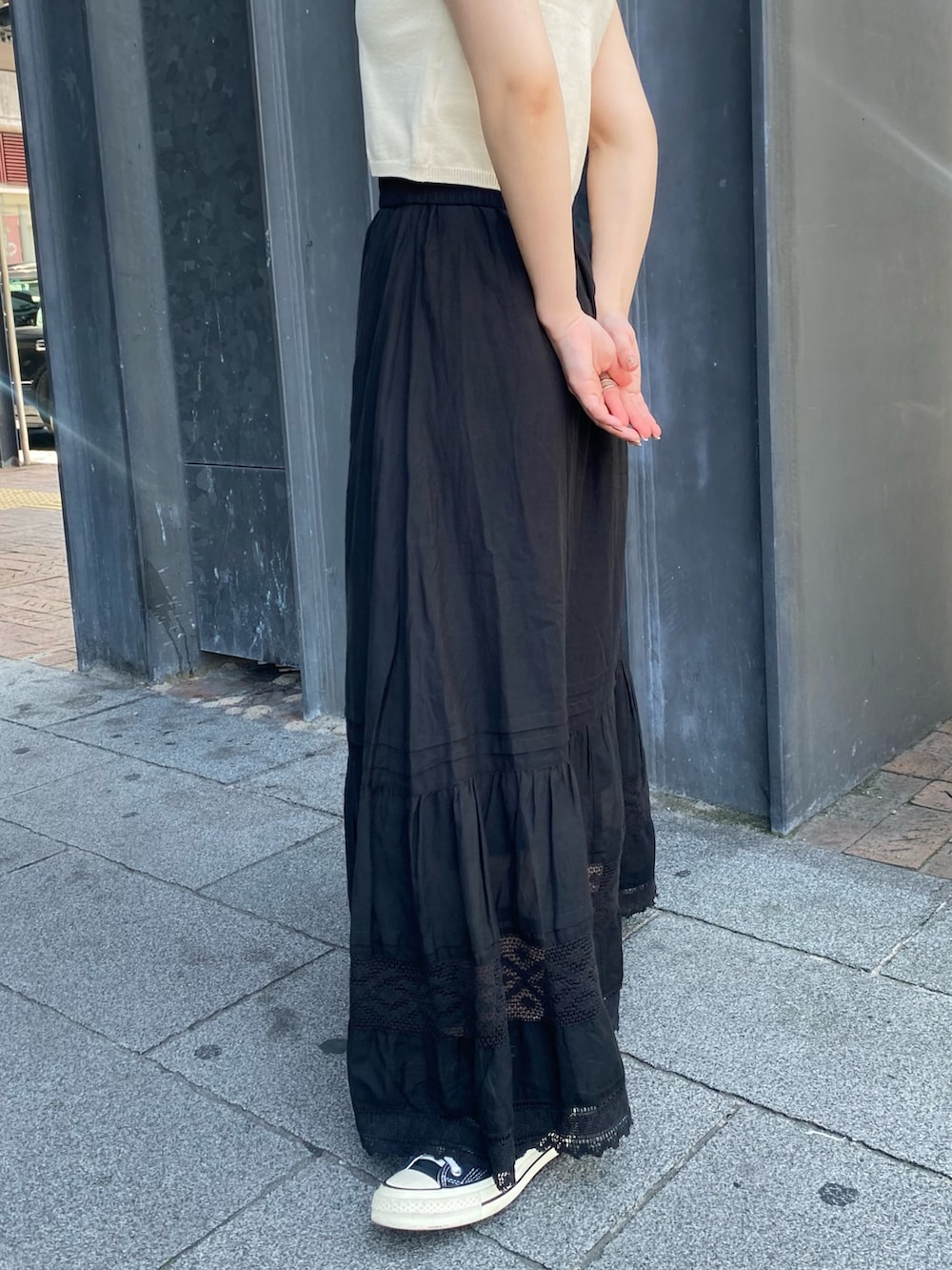 ホワイト系のベスト、ブラック系のスカートを着用したレディースの夏コーディネートの6枚目の写真