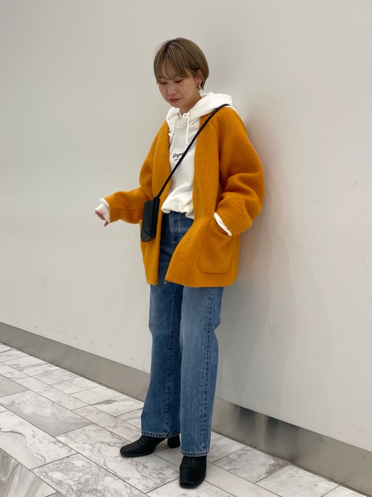 ブルー系のデニムパンツ、イエロー系のテーラードジャケット、ホワイト系のパーカーを着用したレディースの秋コーディネートの4枚目の写真