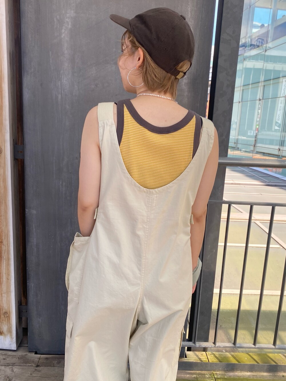 グリーン系のエコバッグ/サブバッグ、イエロー系のタンクトップ、ベージュ系のサロペット/オーバーオールを着用したレディースの夏コーディネートの6枚目の写真