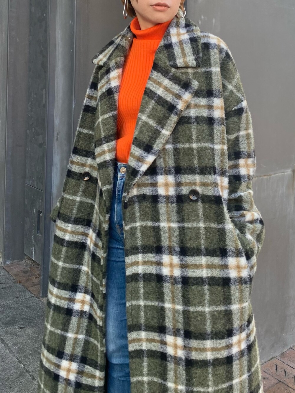 オレンジ系のニット/セーター、ホワイト系のショルダーバッグ、ブルー系のデニムパンツを着用したレディースの秋コーディネートの4枚目の写真