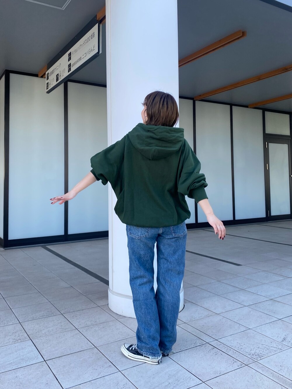 グリーン系のパーカー、ブルー系のデニムパンツを着用したレディースの秋コーディネートの4枚目の写真